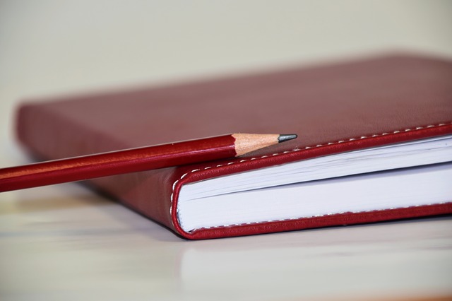 בתמונה ספר אדום עם עיפרון אדום